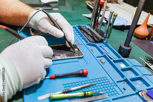 Technician examining damaged mobile phone at workbench at repair shop