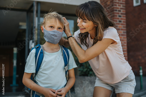 Mother helping son to wear protective face mask while going to school photo