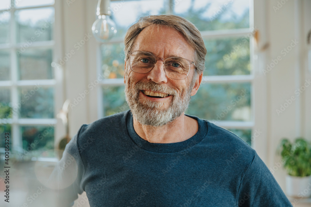 Mature man laughing while standing at home Mature man laughing while standing at home