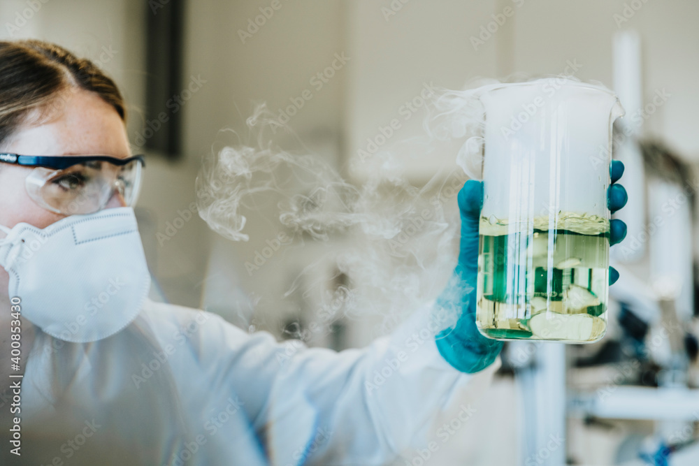 © Mareen Fischinger/Westend61 - Laboratory assistant wearing protective face mask and eyeglasses holding liquid beaker while standing at laboratory © Mareen Fischinger/Westend61 - Laboratory assistant wearing protective face mask and eyeglasses holding liquid beaker while standing at laboratory