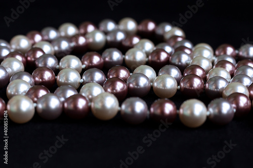 Necklace of pearls of different colors on black velvet.