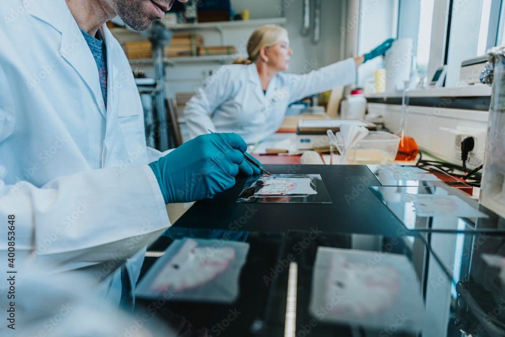 Man working on human brain microscope slide with coworker standing in background at laboratory Man working on human brain microscope slide with coworker standing in background at laboratory