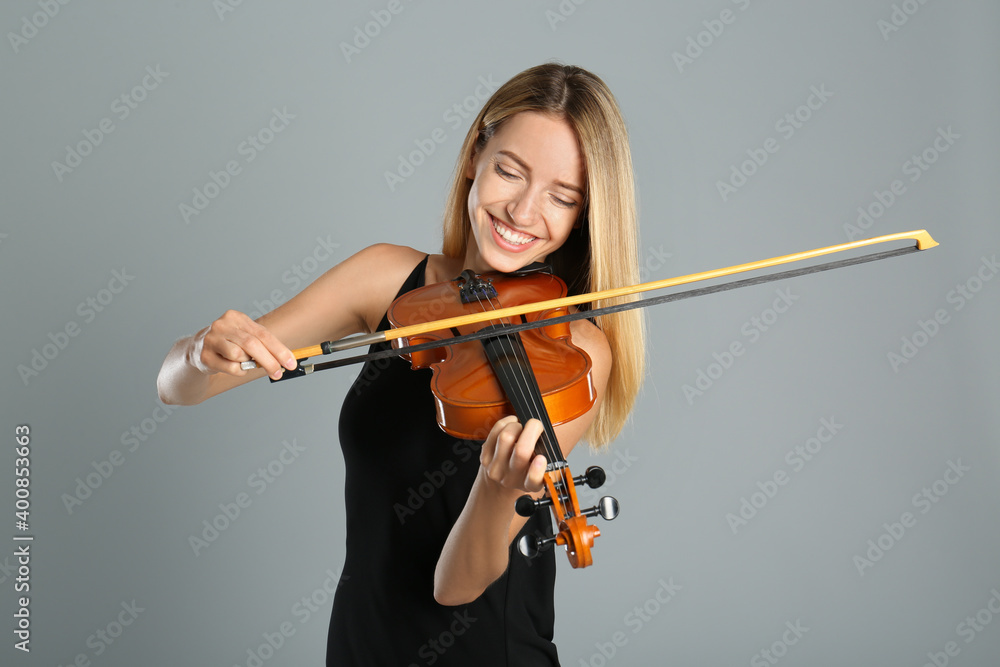 Beautiful woman playing violin on grey background Beautiful woman playing violin on grey background