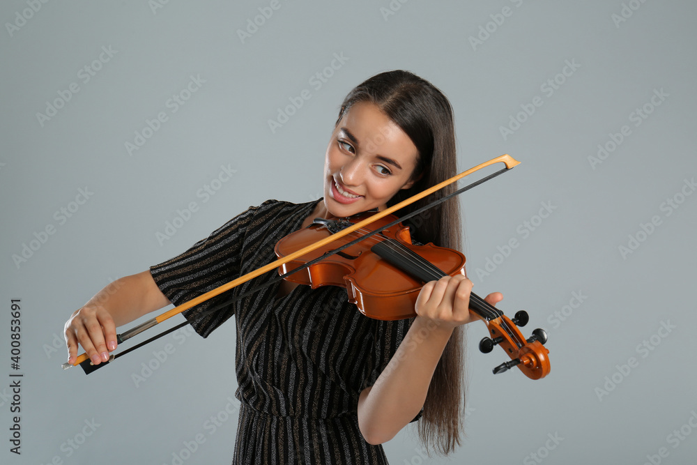 Beautiful woman playing violin on grey background Beautiful woman playing violin on grey background