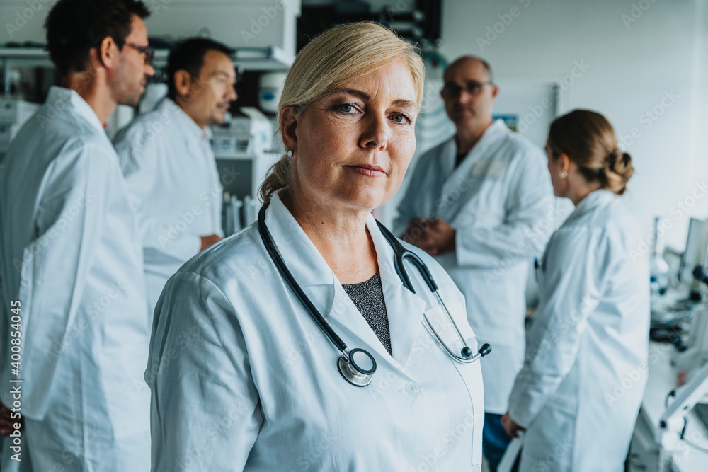 Smiling female scientist looking away while standing with coworker in background at laboratory Smiling female scientist looking away while standing with coworker in background at laboratory