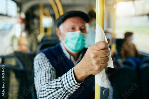 Close-up of senior man commuting by public bus during coronavirus pandemic.
