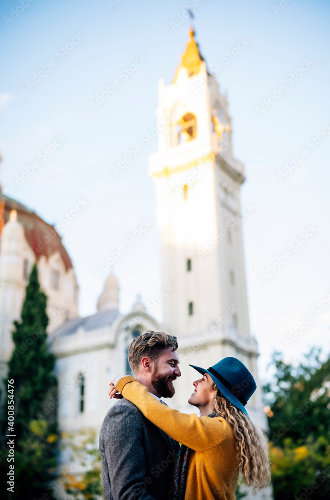 Couple embracing while standing against church in city Couple embracing while standing against church in city