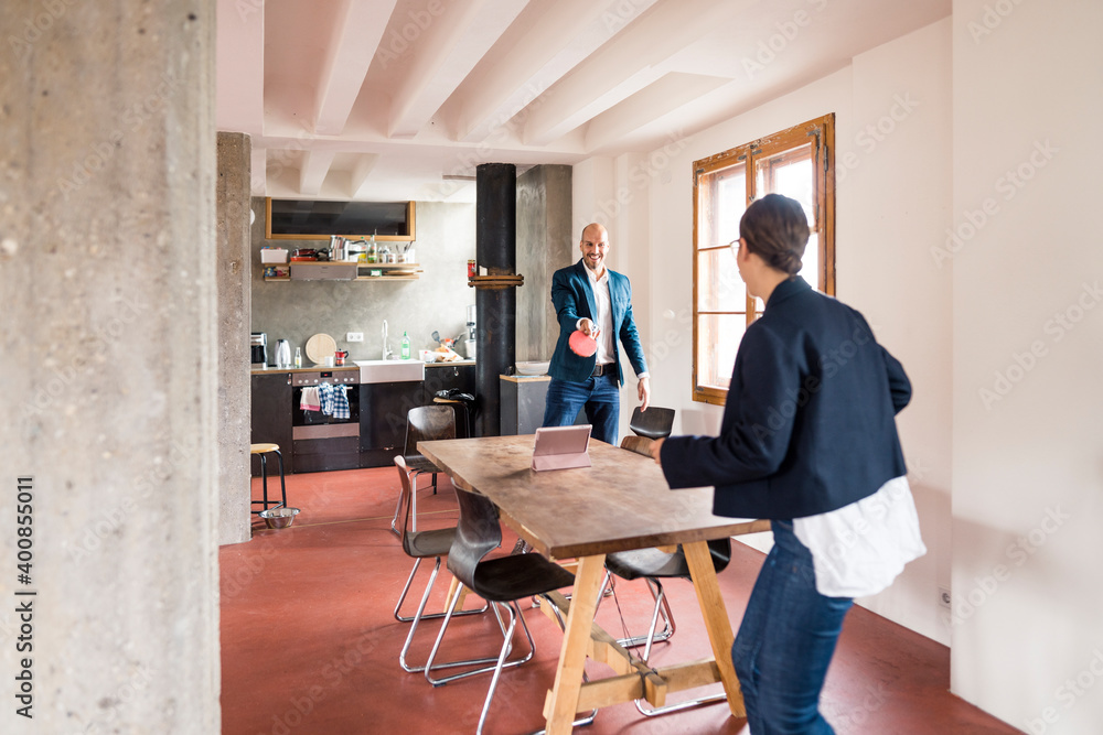 Carefree business people playing table tennis while standing at office Carefree business people playing table tennis while standing at office