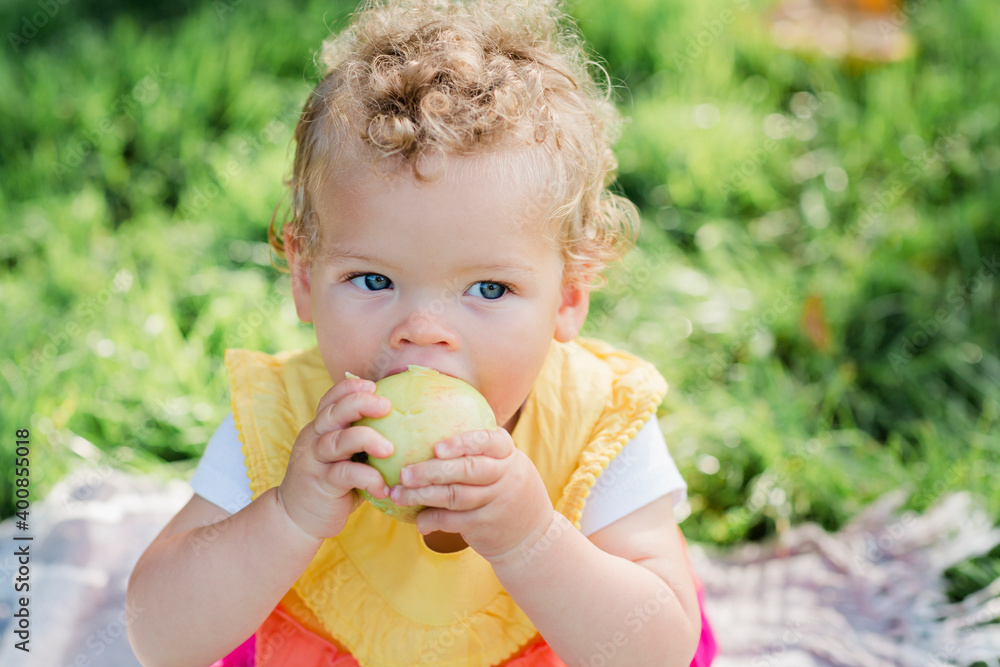Cute baby girl eating fruit while sitting on grass at park Cute baby girl eating fruit while sitting on grass at park