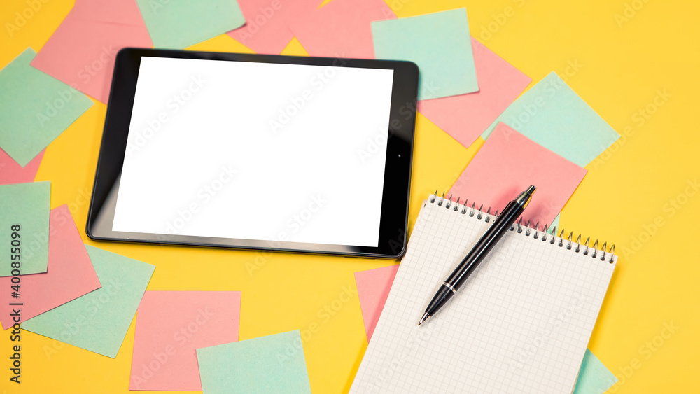 Cropped close up view of mock up image black tablet pc white blank screen isolated yellow bright background. Colorful memo sticky pin clips empty notes scattered in a chaotic manner. Notepad with pen Cropped close up view of mock up image black tablet pc white blank screen isolated yellow bright background. Colorful memo sticky pin clips empty notes scattered in a chaotic manner. Notepad with pen