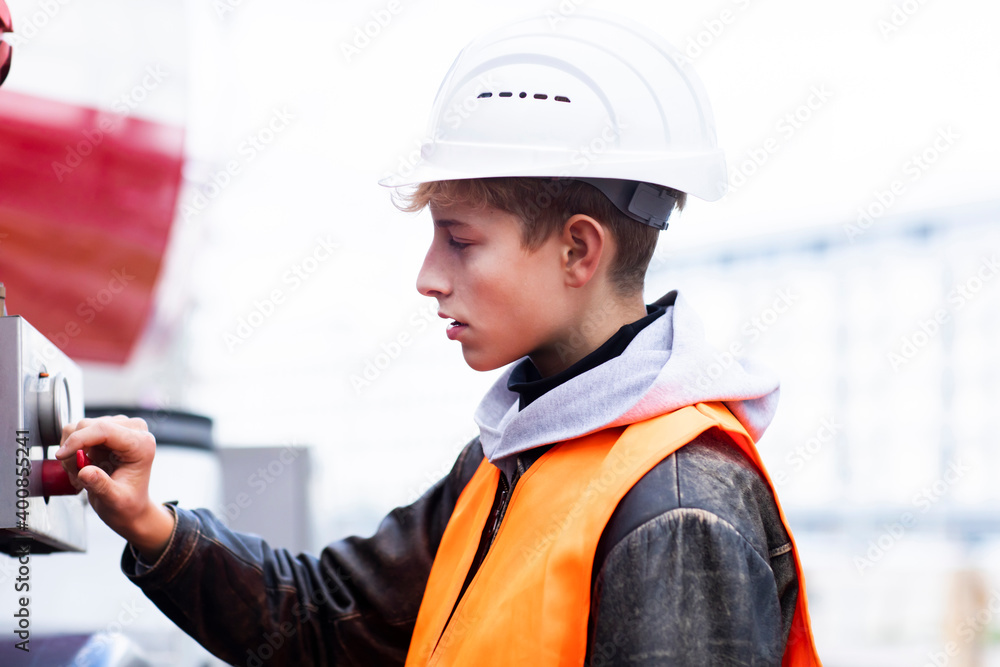 Male teenage trainee using machinery at construction site Male teenage trainee using machinery at construction site
