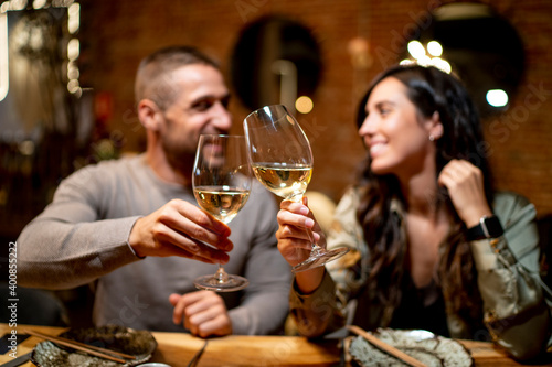 Friends looking at each other while toasting drink at restaurant photo