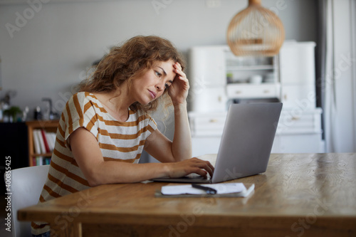 Woman getting frustrated while working on laptop at home