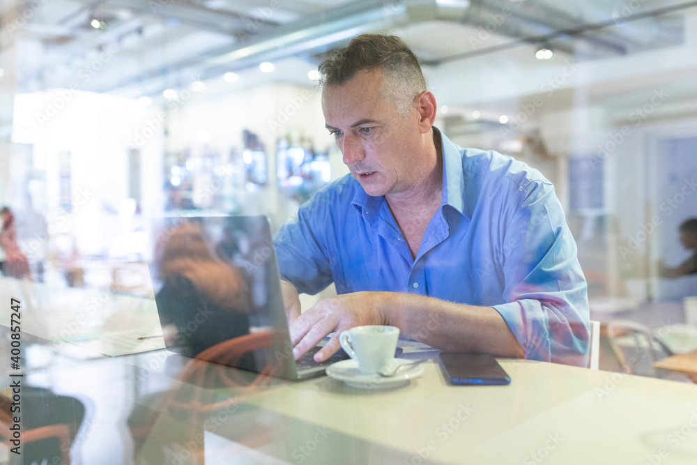 Male entrepreneur using laptop while sitting with coffee in cafe Male entrepreneur using laptop while sitting with coffee in cafe