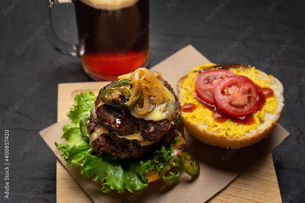 Cheese burger with caramelized onion and jalapeno pepper on dark background