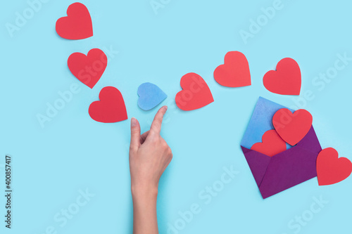 From one envelope go out a lot of red heart with one blue heart that the girl's hand want to catch. love Valentine day on 14th February