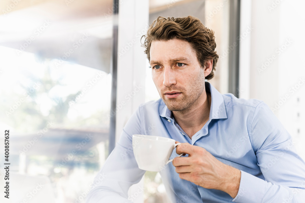 Mid adult man drinking coffee while sitting in office Mid adult man drinking coffee while sitting in office
