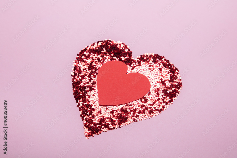 Heart shape made of red glitter and the second paper handmade heart on pink background. Love concept.