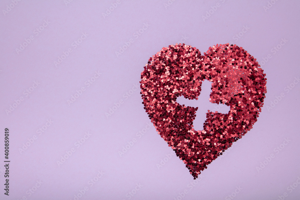 Heart shape made of red glitter on pink background with medical cross . Love concept.