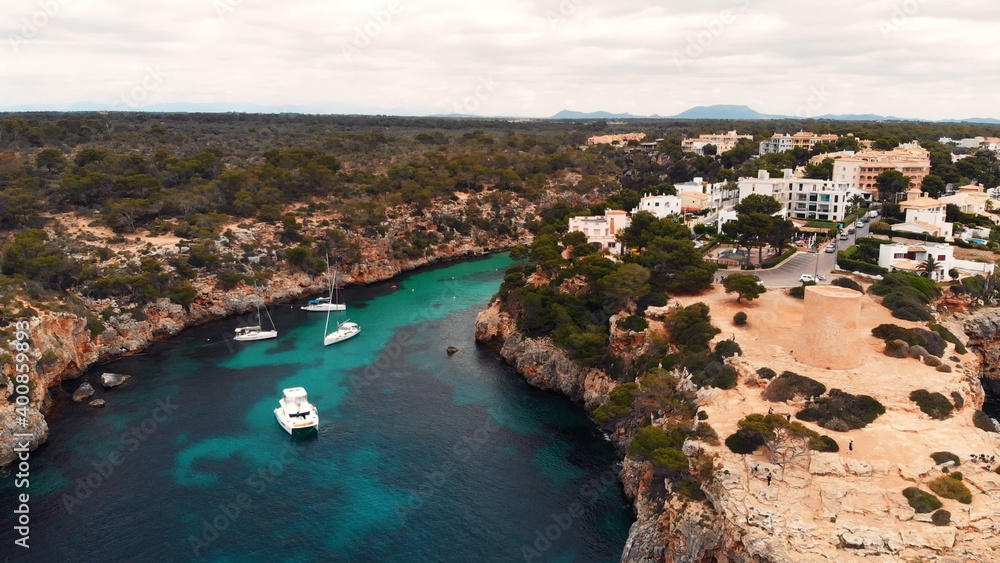 Floating boats in crystal clear Mediterranean sea with coral reef and cliffs, Mallorca, Cala pi, Cala Satanyi, Aerial. High quality photo