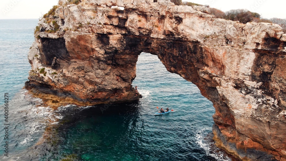 Es Pontas, turist climbling on Natural Rock Arch At The Coast Of Majorca Island, between Cala Santanyi and Cala Llombards, Spain. High quality photo
