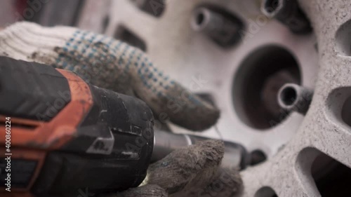 Close-up of replacing a wheel with an electric wrench. Footage. Live footage from the pit stop of the racing rally site.