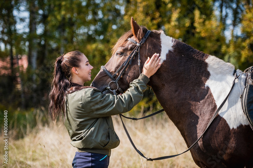 The owner of a horse strokes and caresses her horse on an autumn day on the farm. photo