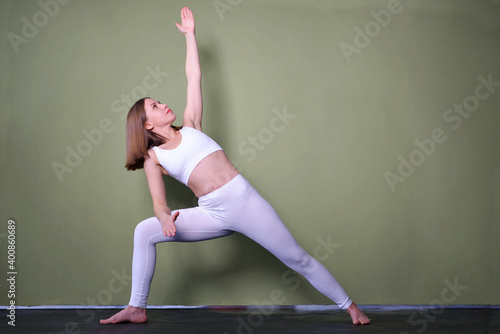 brown-haired woman wearing black sportswear practicing yoga, doing Utthita parsvakonasana exercise on mat, standing in Extended Side Angle pose, beautiful girl working out in yoga studio