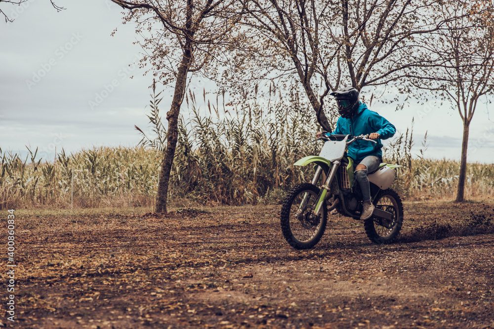 Teenage male riding off-road motorcycle in forest during autumn Teenage male riding off-road motorcycle in forest during autumn