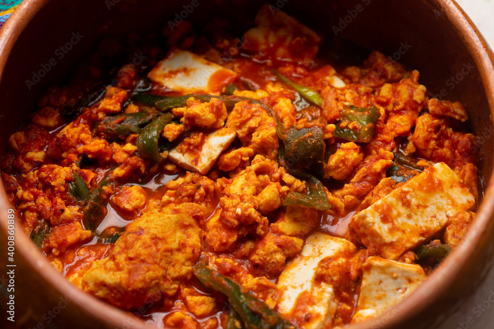 Mexican scrambled eggs in red sauce with poblano pepper and cheese on white background Mexican scrambled eggs in red sauce with poblano pepper and cheese on white background