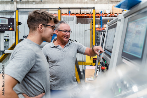 Male engineers brainstorming while testing machine at factory