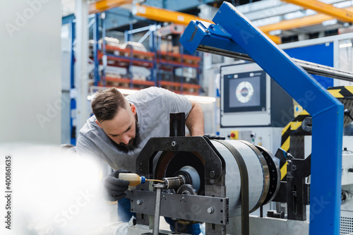 Male technician oiling machinery while examining in industry