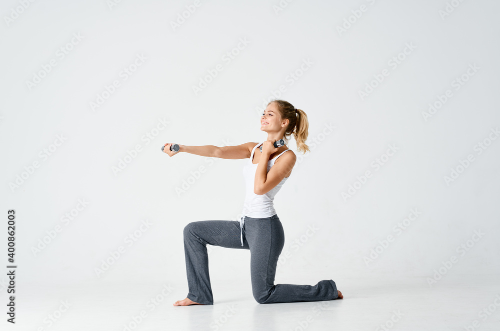 athletic woman sitting on one knee and holding dumbbells in hand fitness sport model