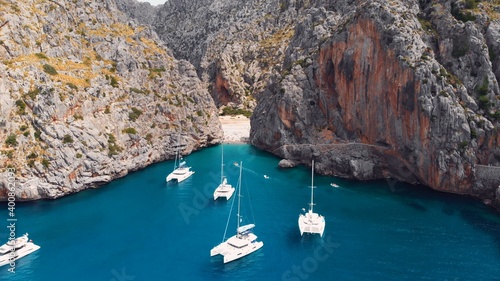 Serra De Tramuntana,Sa Calobra, Torrent De Pareis beach, aerial ,crystal clear water of mediterranean sea with moored sailing boats and yacht going towards the beach. High quality photo photo