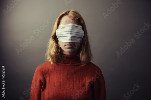 Teenage girl wearing protective face mask on eyes while standing against gray background