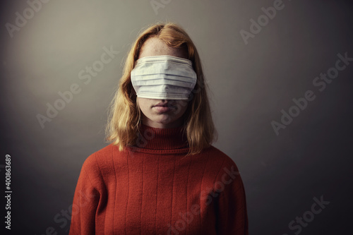 Teenage girl wearing protective face mask on eyes while standing against gray background photo