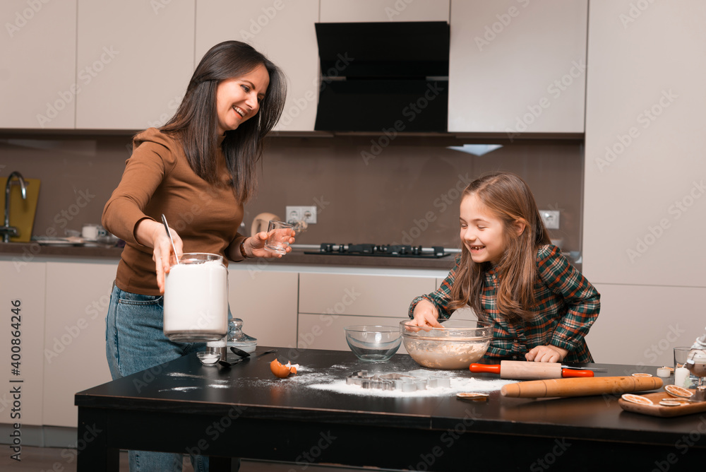 Cheerful mother having time with her daughter and preparing some cookies in kitchen Cheerful mother having time with her daughter and preparing some cookies in kitchen