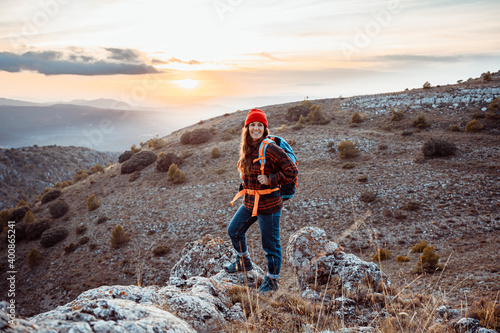 Smiling female hiker looking away while standing on rock mountain during sunset photo