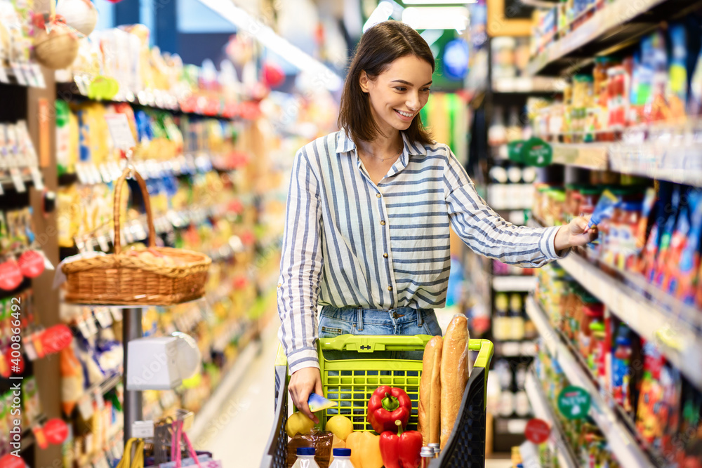 Fototapeta premium Young woman with the cart shopping in grocery store