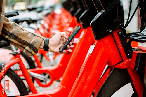 Mans hand holding smart phone to rent bicycle