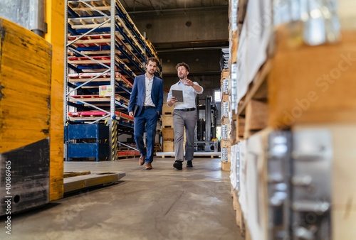 Man using digital tablet while inspecting warehouse with businessman at factory photo