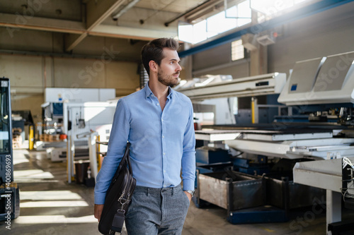 Male entrepreneur with brief case walking at factory photo