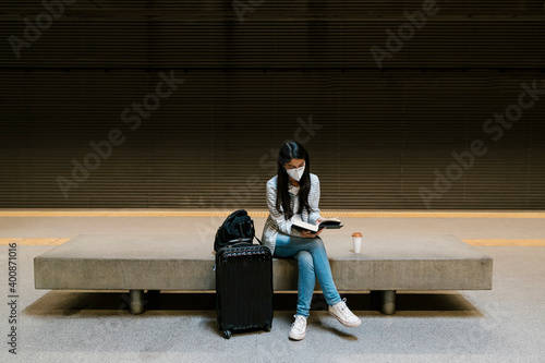 Female passenger reading book while sitting at metro station photo