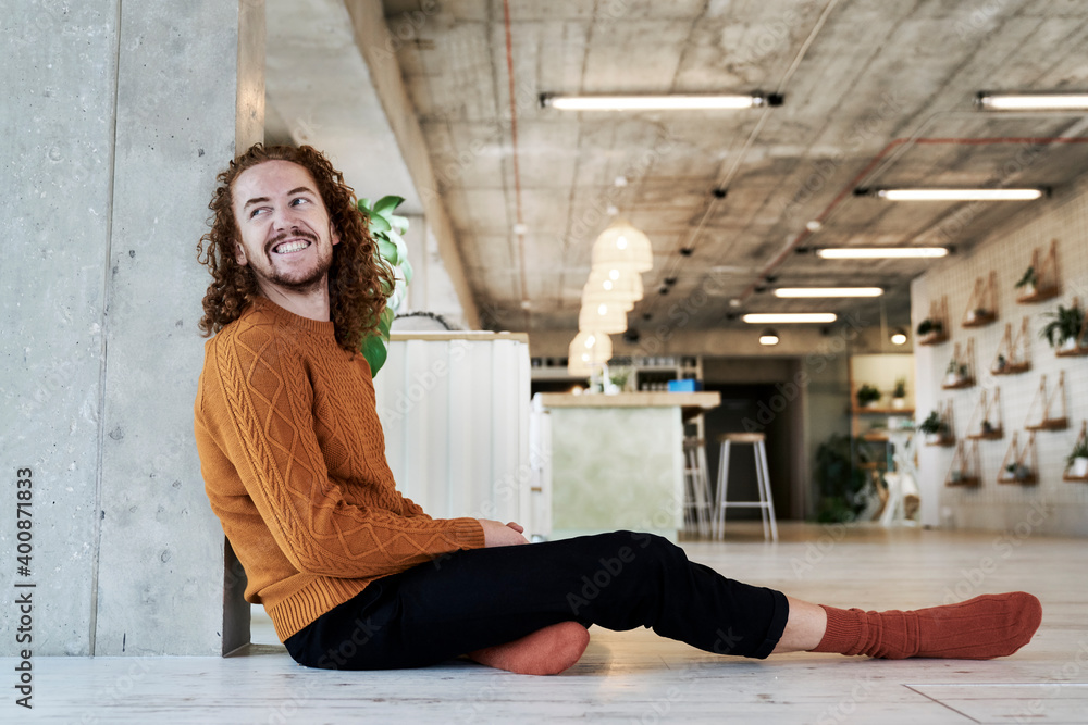 Smiling man looking away while sitting against architectural column in living room at home