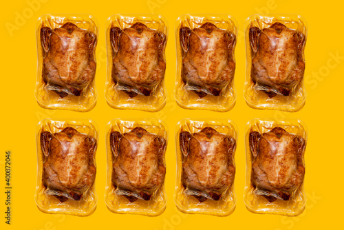Vacuum packed roasted chickens arranged in a row on yellow background