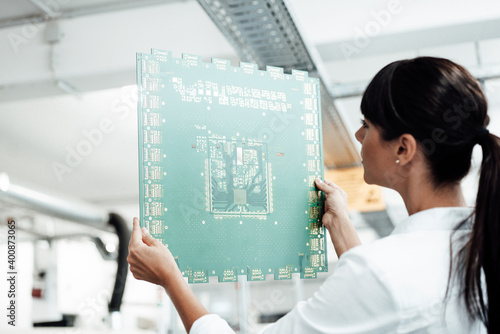 Mature businesswoman analyzing large computer chip in industry photo