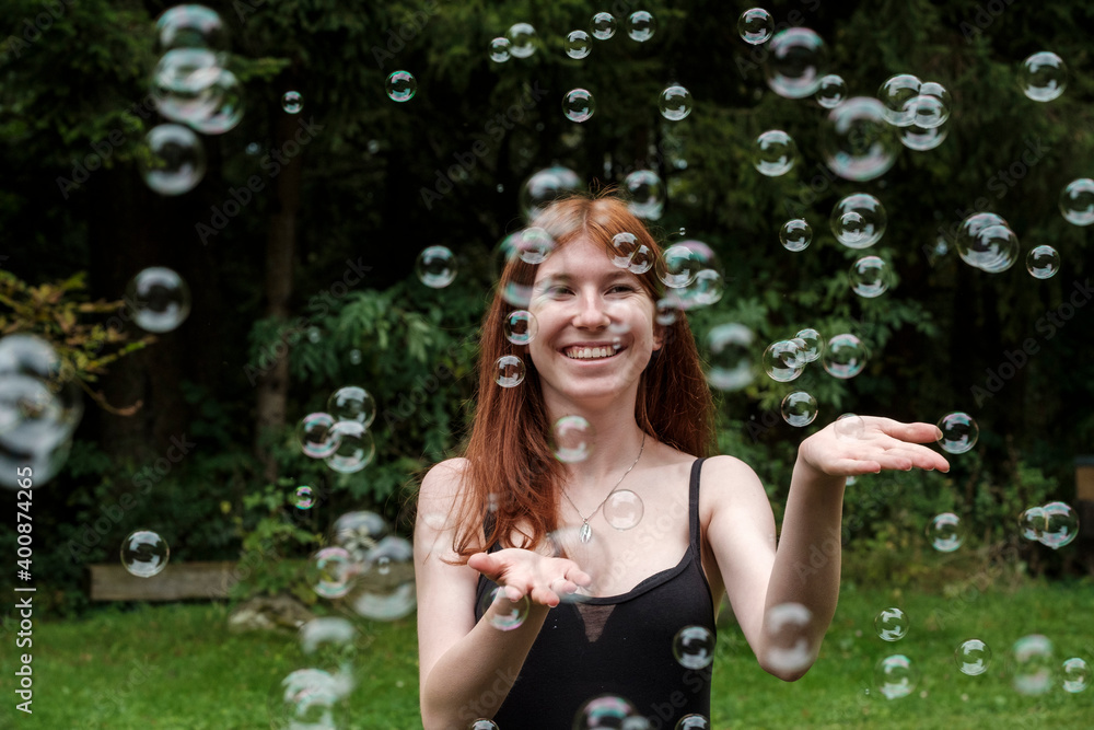Happy woman playing with soap bubbles in yard Happy woman playing with soap bubbles in yard