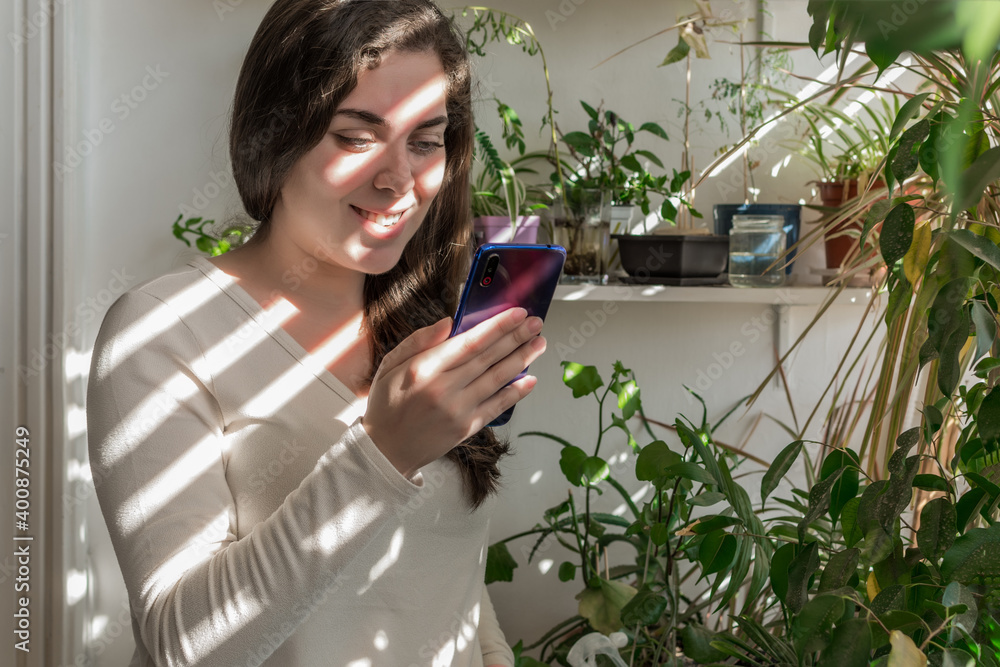Young Caucasian woman using a smart phone on her balcony on a sunny day. Young Caucasian woman using a smart phone on her balcony on a sunny day.