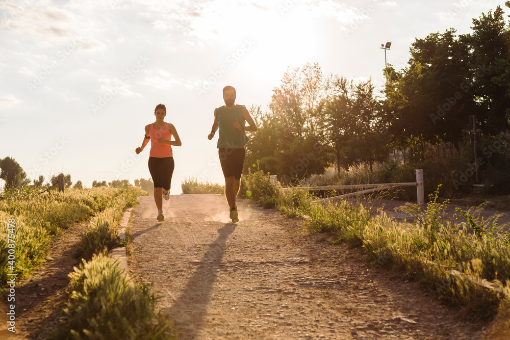 Active young couple jogging in park during sunset Active young couple jogging in park during sunset