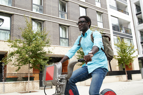 Smiling mature man with backpack commuting on bicycle in city photo